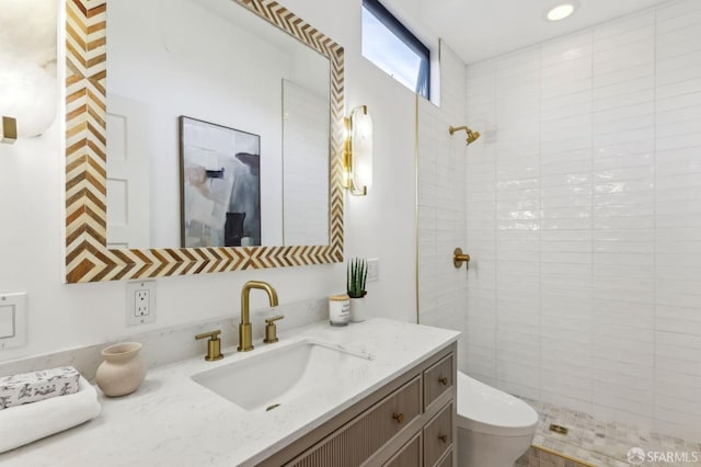 full bathroom with toilet, tiled shower, and vanity