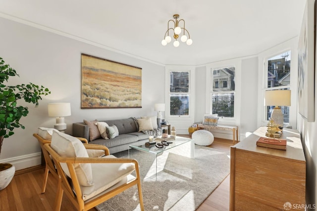 living area with baseboards, crown molding, an inviting chandelier, and wood finished floors