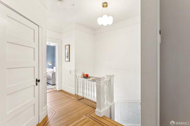 corridor featuring a wainscoted wall, a notable chandelier, and wood finished floors