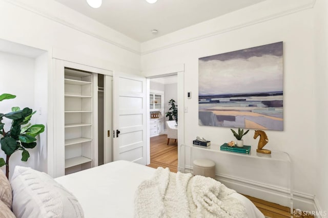 bedroom featuring crown molding, a closet, and wood finished floors