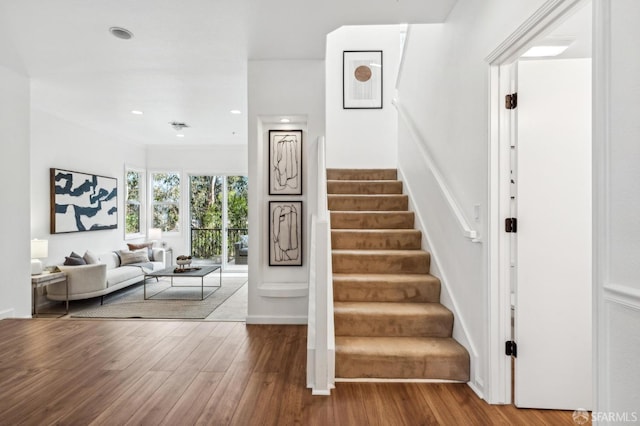 stairway with recessed lighting and wood finished floors