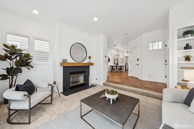 living room with crown molding, a tiled fireplace, baseboards, and recessed lighting