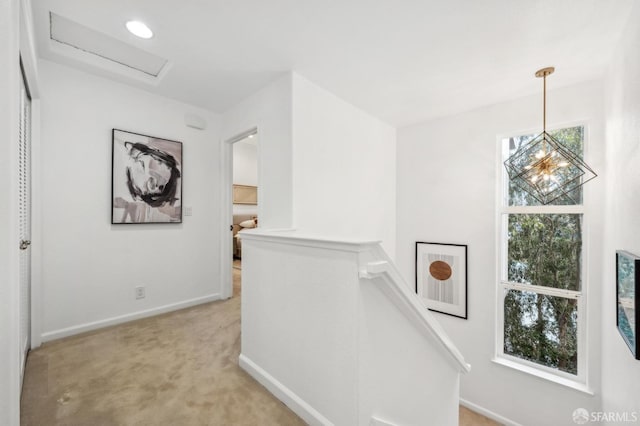 hall with baseboards, attic access, an upstairs landing, and light colored carpet