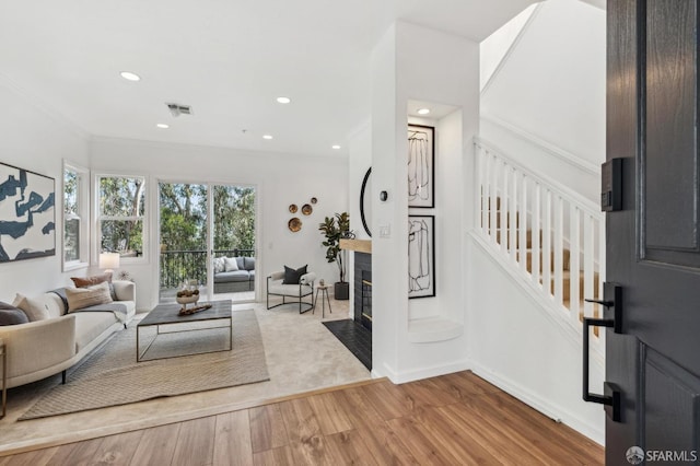 living room with visible vents, a fireplace with flush hearth, wood finished floors, baseboards, and stairs