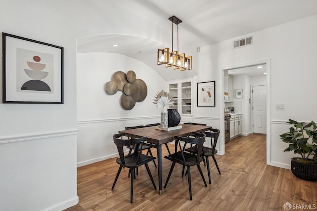 dining room featuring a notable chandelier, wood finished floors, visible vents, and baseboards