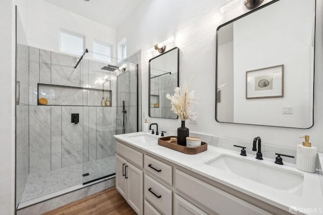 bathroom featuring double vanity, a marble finish shower, a sink, and wood finished floors