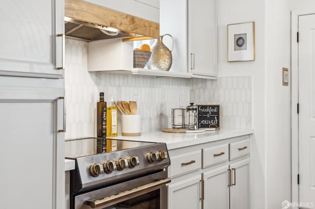 kitchen with open shelves, light countertops, decorative backsplash, high end range, and wall chimney exhaust hood