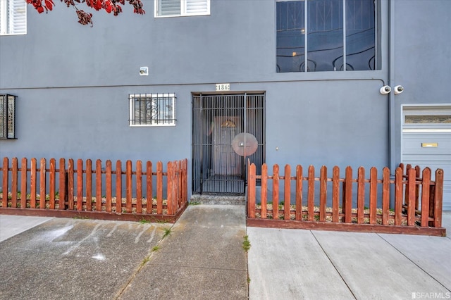 entrance to property with fence and stucco siding