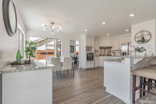 4156 N Amargosa Dr N, Antioch, CA 94531 - kitchen with appliances with stainless steel finishes, wood finished floors, a breakfast bar area, a peninsula, and a chandelier
