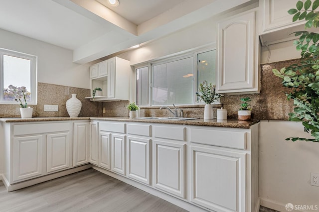 1567 44th Ave, San Francisco, CA 94122 - kitchen featuring white cabinets, backsplash, light wood-style flooring, dark stone counters, and beamed ceiling