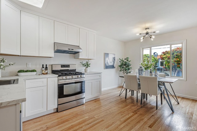1567 44th Ave, San Francisco, CA 94122 - kitchen featuring stainless steel gas range, exhaust hood, a chandelier, light wood-style flooring, and white cabinets