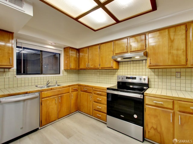 1279 41st Ave, San Francisco, CA 94122 - kitchen featuring appliances with stainless steel finishes, under cabinet range hood, tile countertops, and backsplash