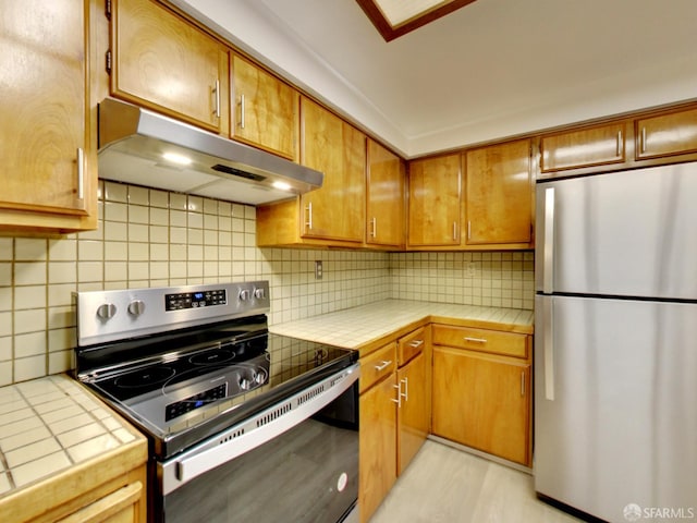 1279 41st Ave, San Francisco, CA 94122 - kitchen featuring stainless steel appliances, under cabinet range hood, tile countertops, and decorative backsplash