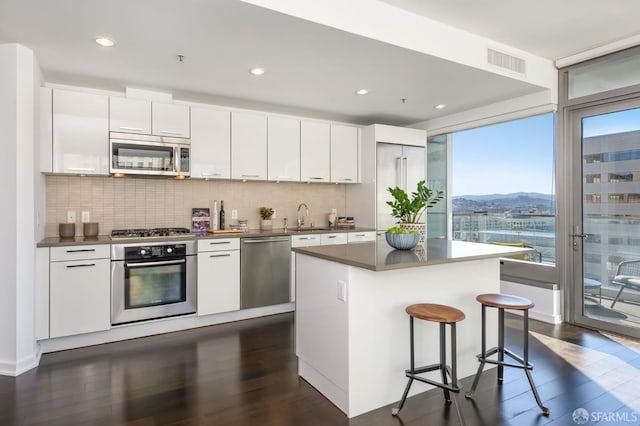 1 Hawthorne St Unit 12F, San Francisco, CA 94105 - kitchen with stainless steel appliances, dark wood-style floors, backsplash, a kitchen breakfast bar, and recessed lighting