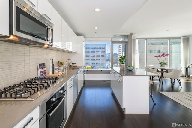 1 Hawthorne St Unit 12F, San Francisco, CA 94105 - kitchen with modern cabinets, appliances with stainless steel finishes, white cabinetry, a kitchen breakfast bar, and tasteful backsplash