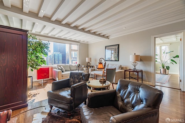 living room with light hardwood / wood-style floors, beam ceiling, and plenty of natural light