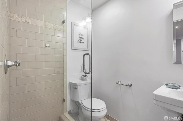 bathroom featuring an enclosed shower, sink, and toilet