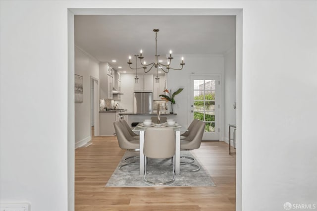 dining space with ornamental molding, a chandelier, and light wood-type flooring