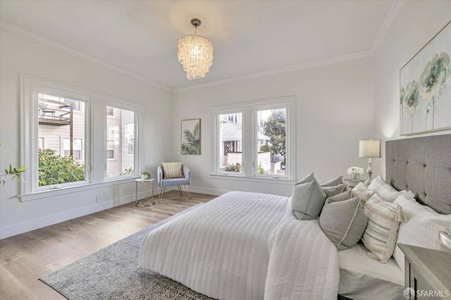 bedroom featuring multiple windows, ornamental molding, light hardwood / wood-style floors, and a chandelier