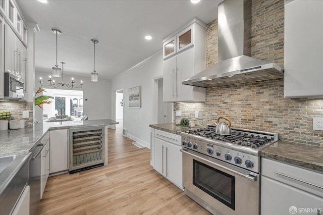 kitchen with white cabinetry, appliances with stainless steel finishes, wall chimney exhaust hood, and beverage cooler