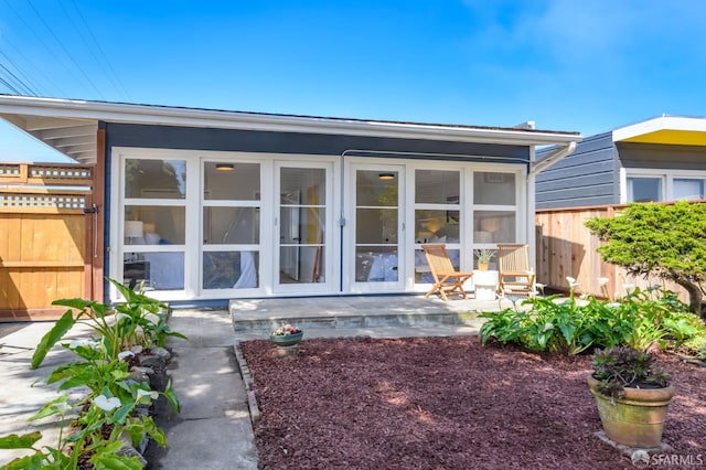 rear view of property featuring fence and a sunroom