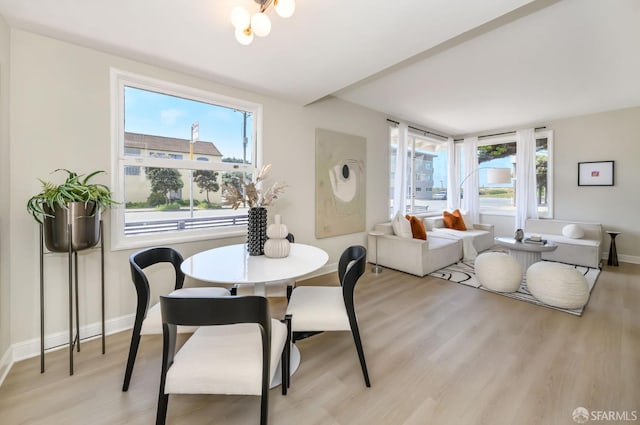 dining room with light wood-style floors, baseboards, and an inviting chandelier