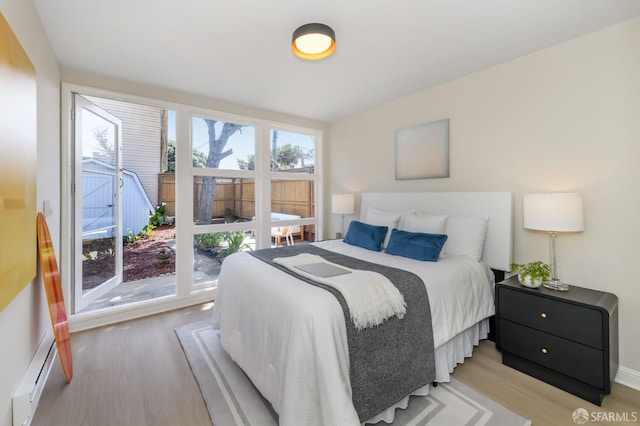 bedroom with light wood finished floors and a baseboard heating unit