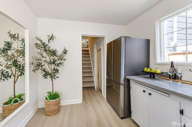kitchen with freestanding refrigerator, light wood finished floors, and white cabinetry