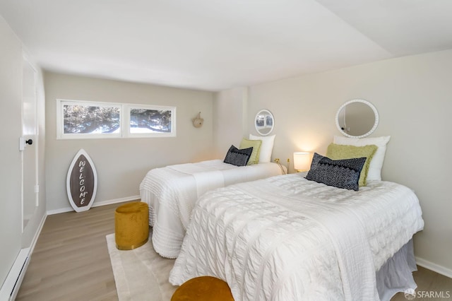 bedroom with baseboards, wood finished floors, and baseboard heating