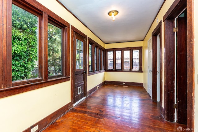 unfurnished sunroom featuring baseboards and hardwood / wood-style flooring