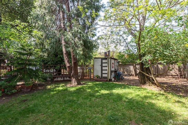 view of yard with an outdoor structure, a fenced backyard, and a shed