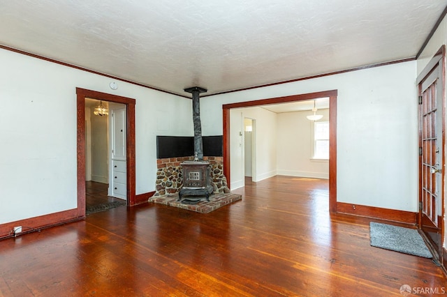 unfurnished living room with baseboards, a wood stove, and hardwood / wood-style floors