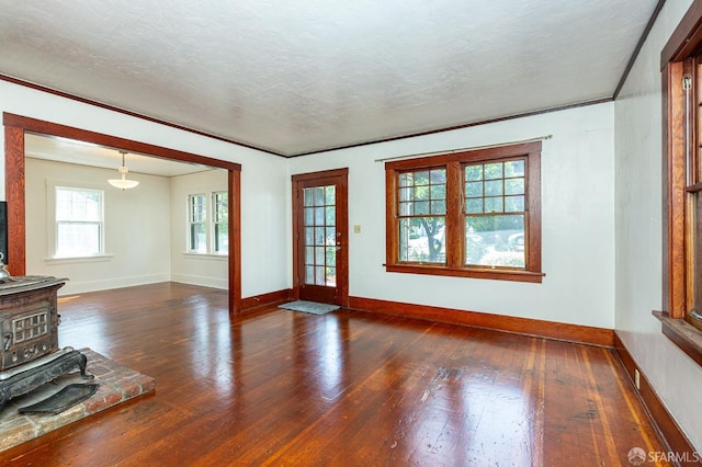 unfurnished living room with baseboards, a wood stove, and hardwood / wood-style floors