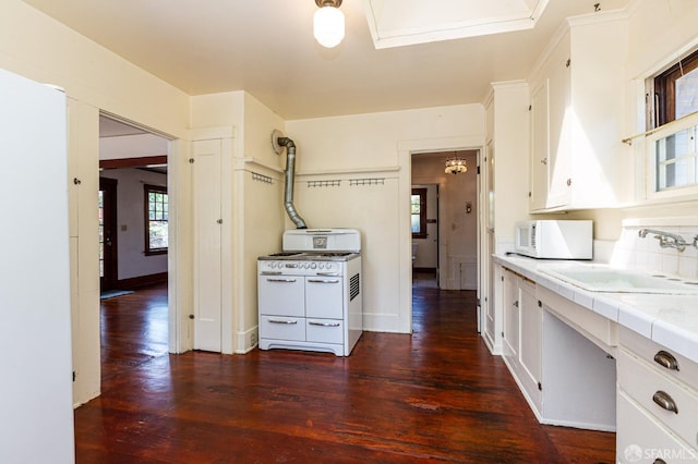 kitchen featuring white appliances, dark wood-style floors, tile countertops, white cabinetry, and a sink