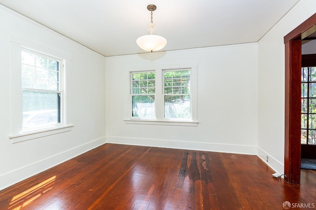 spare room with wood-type flooring, baseboards, and a healthy amount of sunlight