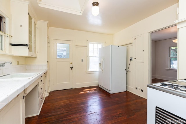 kitchen featuring a sink, tile counters, range, dark wood finished floors, and white fridge with ice dispenser