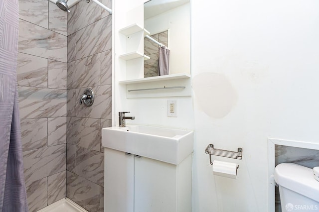 bathroom with vanity, a tile shower, and toilet