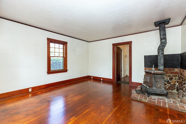 unfurnished living room featuring crown molding, baseboards, hardwood / wood-style flooring, and a wood stove