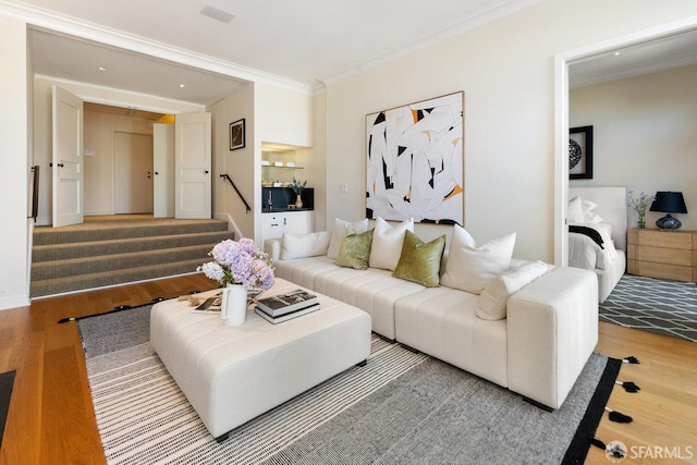living area featuring wood finished floors, stairs, and ornamental molding