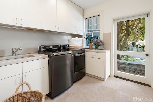 clothes washing area with a sink, cabinet space, light floors, and washing machine and clothes dryer