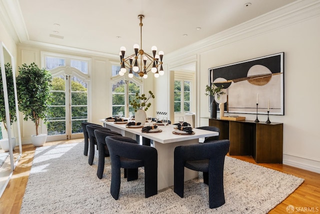 dining space featuring a chandelier, baseboards, light wood-style floors, and ornamental molding