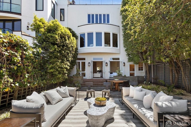 rear view of property featuring stucco siding, fence, and an outdoor hangout area