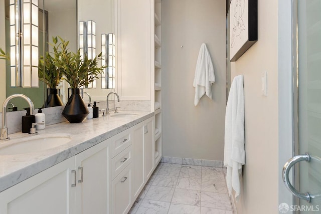 bathroom featuring double vanity, marble finish floor, baseboards, and a sink