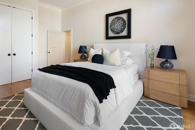 bedroom with wood finished floors, a closet, and ornamental molding