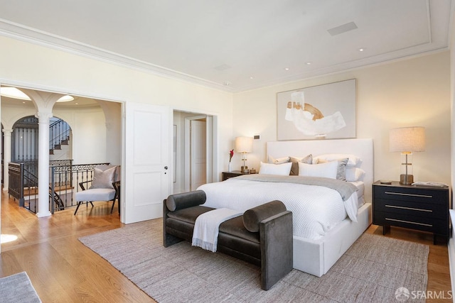 bedroom featuring crown molding, wood finished floors, and arched walkways