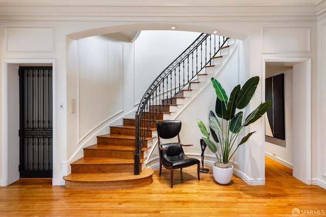 stairway with baseboards, arched walkways, and wood finished floors