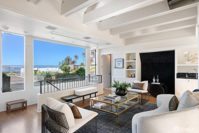 living area featuring beam ceiling, built in features, visible vents, and wood finished floors