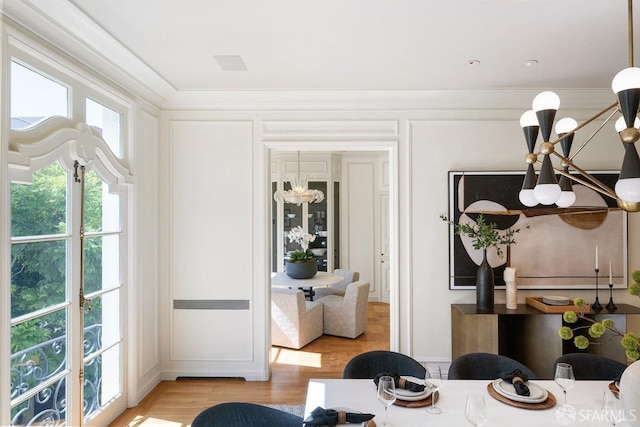dining space with a chandelier, a decorative wall, light wood-style floors, and ornamental molding