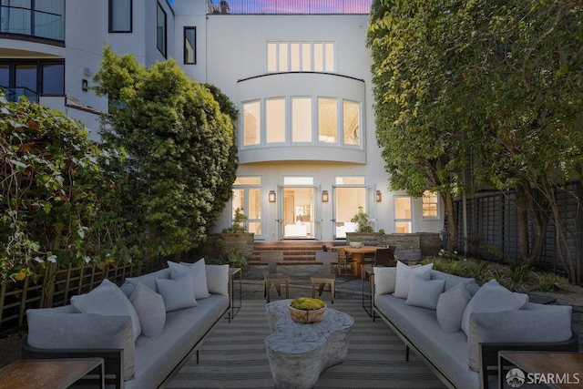 rear view of property featuring an outdoor living space, stucco siding, and fence