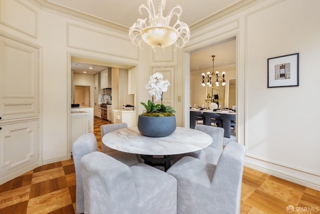 dining room featuring a notable chandelier, crown molding, and a decorative wall